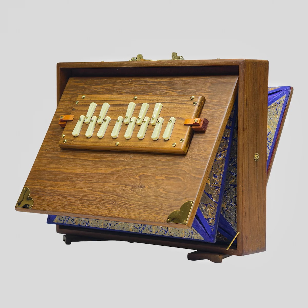 Right side angle of an open acoustic drone box showing brass corners and teak wood construction